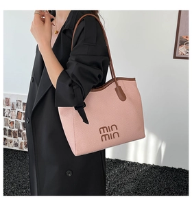 Detail of pink woven tote bag with brown leather handles worn by a model