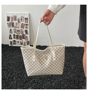 Détail d'un cabas beige à monogramme avec un nœud doré et une poignée de transport