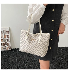 Détail du sac cabas blanc cassé avec motif M et ornement de nœud doré élégant