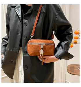 Detail of caramel frosted leather crossbody bag with unique silver robot pendant