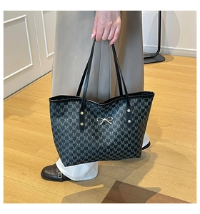 Gros plan sur un grand sac cabas avec motif monogramme M et nœud doré élégant