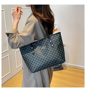 Détail d'un grand sac cabas gris à motifs avec breloque nœud doré porté par un mannequin
