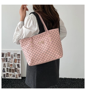 Détail d'un cabas rose clair à motif M et fermoir noeud doré porté par un mannequin