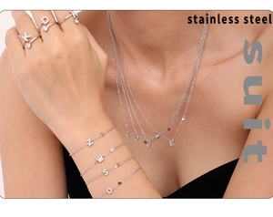 Macro view of crystal-encrusted stainless steel alphabet jewelry set on model skin