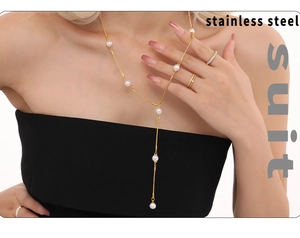 Détail d'un élégant collier en Y en acier doré avec perles blanches et bagues dorées
