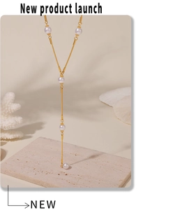 Détail du collier en Y doré orné de perles blanches sur une chaîne minimaliste