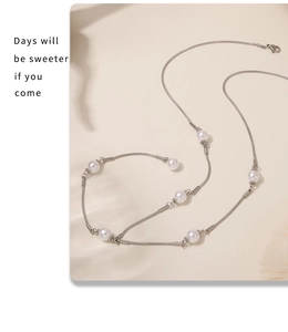 Détail d'une chaîne serpent argentée avec perles et fermoir mousqueton sur fond beige