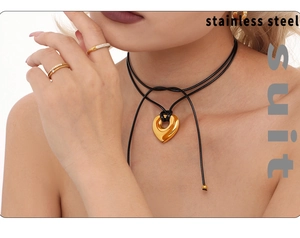 Détail du collier à pendentif cœur et des bagues dorées portés par un mannequin
