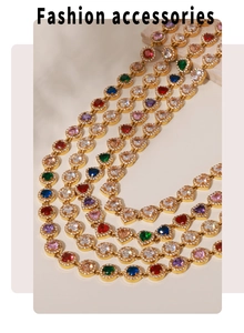 Détail de colliers dorés multicouches avec zircons colorés en forme de cœur