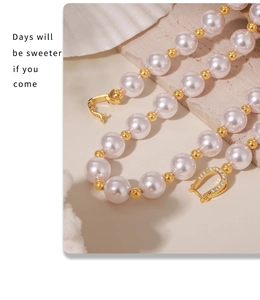 Gros plan d'un collier de perles avec perles dorées et fermoir fer à cheval serti de strass