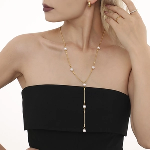 Collier élégant en Y doré avec perles blanches sur chaîne serpent porté par un mannequin