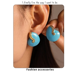 Detailed view of asymmetric turquoise enamel ear studs with gold plating and rhinestones
