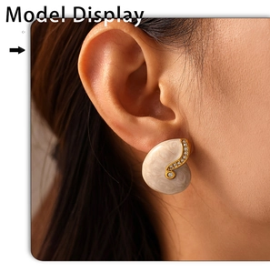 Detail of vintage shell-shaped earring with white enamel and zircons on model ear