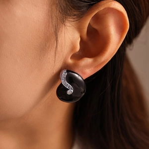 Elegant black enamel S-curve stud earrings with sparkling white crystals on model