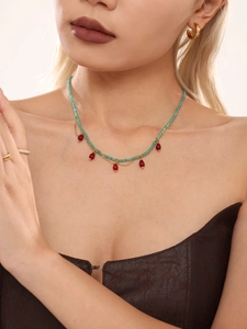 Detail of beaded tassel necklace with green beads and brownish teardrop pendants