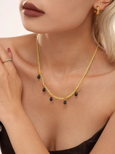 Detail of handmade beaded necklace with blue teardrop stones and gold chain accents