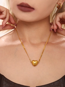 Primo piano della collana dorata con ciondolo a cuore e catena a serpente da donna