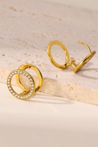 Detalle de pendientes de doble aro chapados en oro PVD con circonitas sobre piedra