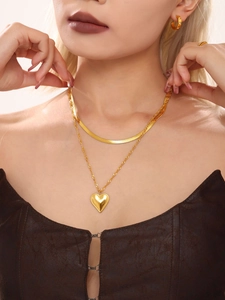 Detail shot of the layered gold heart pendant necklace with snake chain and matching earrings