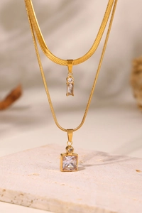 Detail of double-layered gold necklaces with square and rectangular zircon pendants