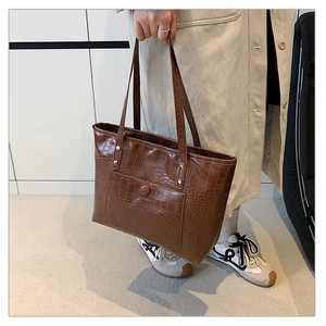 Detail of vintage brown tote bag featuring crocodile embossed texture and front buckle pocket