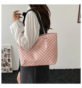 Detail of pink tote bag with M-letter pattern, metal bow charm and rivet accents