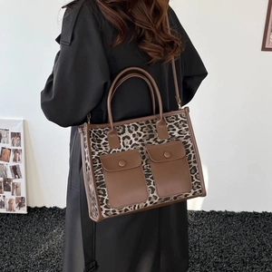 Fashionable leopard print tote bag with brown leather handles and front buckled pockets