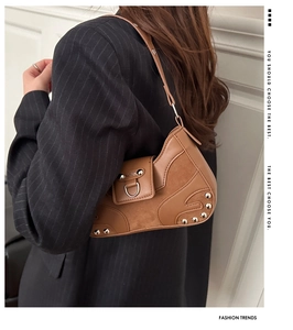 Brown leather underarm bag with silver studs and D-rings shown on a model