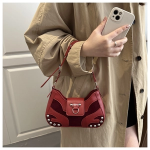 Detail of red vintage handbag featuring shiny leather and suede patchwork with silver studs