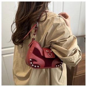 Detail view of red leather underarm bag featuring silver rivets and metal buckle design