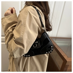 Detail view of black vintage underarm bag with silver rivets and leather patchwork