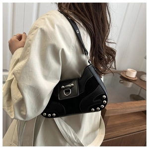 Detail of silver rivets and metallic ring on black leather punk style underarm crescent bag