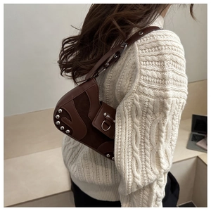 Detail view of brown leather saddle bag with silver studs and adjustable strap on a model