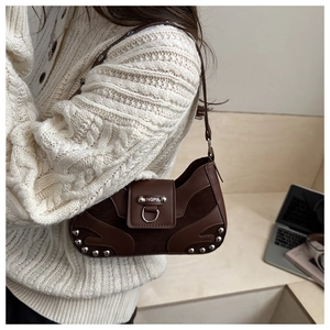 Close-up of brown leather shoulder bag with silver studs and metal ring detail