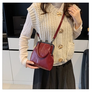 Detail of dark red vintage shell bag with textured leather and retro clasp closure