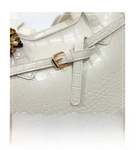 Detail of white crocodile embossed tote with gold buckle and decorative silk scarf