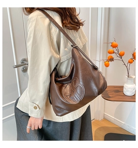 Detailed close-up of dark brown soft leather shoulder bag featuring a large embossed B logo