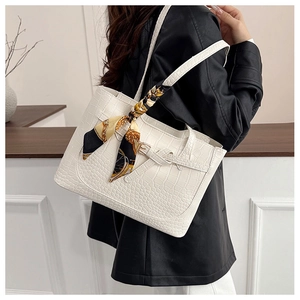 Detail of white crocodile pattern tote bag with yellow silk scarf on the handle