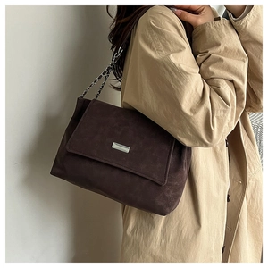 Détail du sac cabas en daim marron foncé avec chaîne argentée et boucle en métal