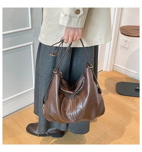 Detail of dark brown vintage leather tote with embossed logo and golden metal hardware