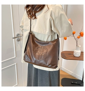 Detail of dark brown leather tote bag showing vintage texture and embossed logo logo