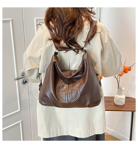 Deep brown leather hobo bag with vintage embossed geometric detail on model shoulder