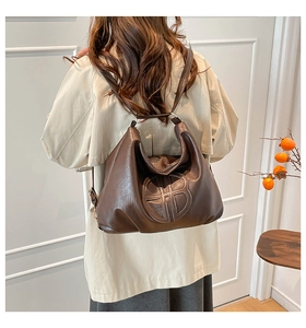 Dettaglio della borsa tote in pelle marrone scuro con logo inciso indossata da modella