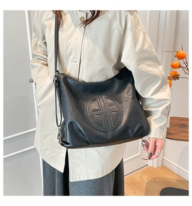 Detail of black large capacity hobo bag with embossed round logo and adjustable strap