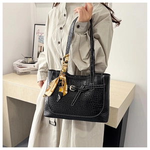 Detail of black crocodile pattern tote bag featuring decorative silk scarf and metal buckle