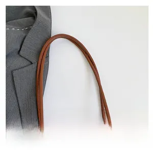 Detail of blue woven fabric texture and brown leather handle on a large tote bag