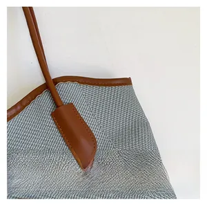 Macro detail of woven gray fabric texture with premium brown leather stitching and edging