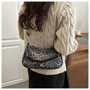 Dettaglio della borsa leopardata con catena dorata su un maglione in maglia crema