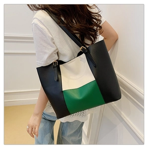 Detail of color-block tote bag with adjustable black straps and gold buckles for women