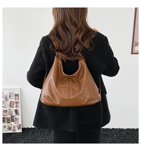 Detailed view of brown leather tote bag with embossed geometric pattern on black coat